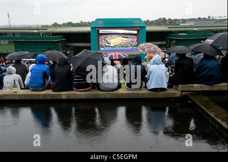 Menschenmassen beobachten die Leinwand auf Aorangi Terrasse oder Henman Hill im Regen während der 2011 Wimbledon Tennis Championships Stockfoto