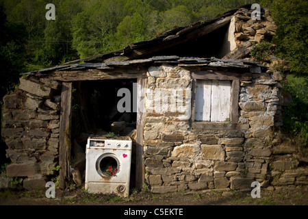 Eine kaputte Waschmaschine blockiert die Tür von einem verlassenen Haus befindet sich in der französische Weg von St. James Weg, Galicien, Spanien. Stockfoto