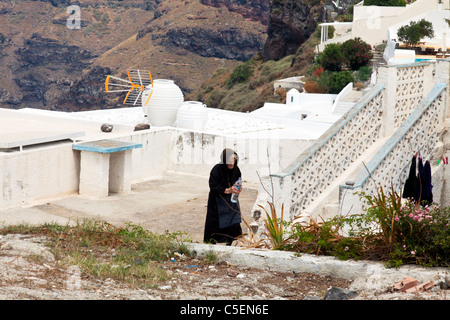 Thira, Santorini, griechische Insel, Griechenland, Europa alte Dame tragen alle schwarz in Trauer Holding Wasserflasche Stockfoto