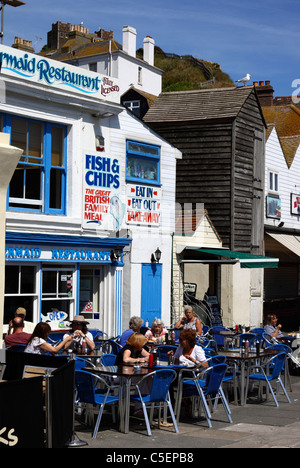 Menschen essen Fisch und Chips vor dem Mermaid Restaurant auf der Rock-A-Nore Road in der Altstadt, Hastings, East Sussex, England Stockfoto