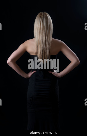 Rückansicht von einer Frau, die Hände auf den Hüften Stockfoto