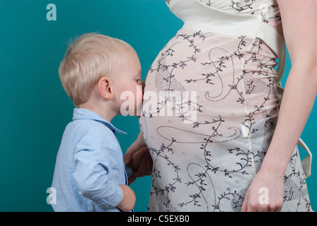 Niedliche kleine Blondschopf seine schwangere Mutter Bauch küssen Stockfoto