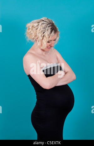 Schwangere Frau Arme verschränkt, Blick auf den Bauch Stockfoto