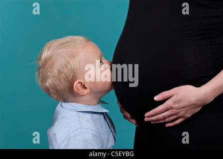 Kleinen blonden Jungen küssen seine schwangere Mutter Bauch Stockfoto