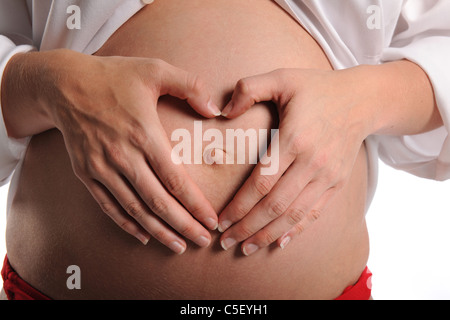 Schwangere Frau, Herzform mit Händen über ihren Bauch isoliert auf weißem Hintergrund Stockfoto