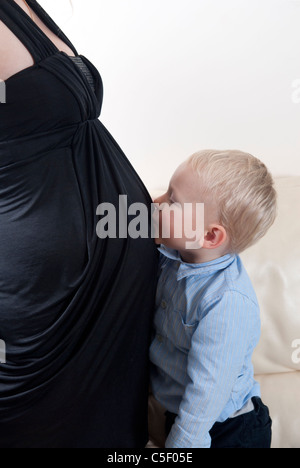 Kleiner Junge küssen seine schwangere Mutter Bauch Stockfoto