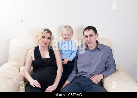 Schwangere Frau saß auf dem Sofa mit ihrem Sohn und Ehemann Stockfoto