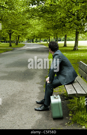 Mann im Anzug saß auf der Bank wegschauen Stockfoto