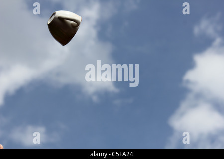 eine fallende Tasse vor einem wolkenverhangenen Himmel blau, Konzeptbild, Metapher Stockfoto