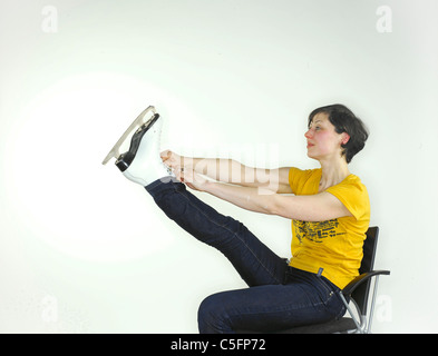 Eine junge kaukasischen Frau anziehen ein Schlittschuh, hielt ihr Bein hoch, die Schnürsenkel zu binden. Stockfoto