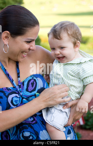 Eine junge Mutter kitzelt ihr Baby glücklich. Stockfoto