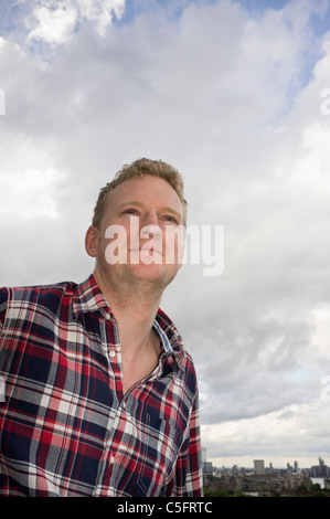 Moderner junger Mann im Alter von dreißig Jahren, der ein modisches Karohemd im Outdoor-Portrait aus einer Kamera mit niedriger Ausrichtung trägt. England Großbritannien Stockfoto