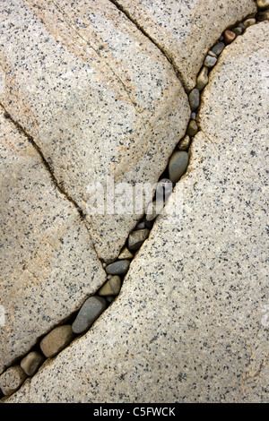 Eingeschlossenen Steinen im Riss in großen glatten Skye weißen Marmorfelsen auf Camas Malag Strand, Isle Of Skye, Schottland, UK Stockfoto