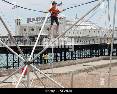 Junge auf einem Bungee-Trampolin vor Brighton Pier Stockfoto