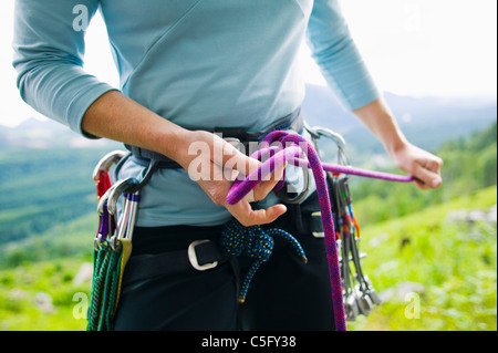 Ein Fenale Kletterer in ihrem Gurtzeug mit einem acht-Knoten binden. Stockfoto