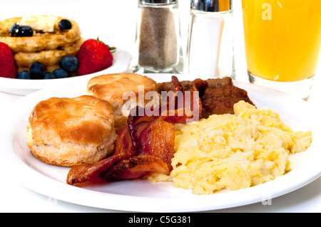 Großen Land-Frühstück mit Rührei, Speck, Buttermilch Kekse, Waffeln, Obst und Orangensaft. Stockfoto