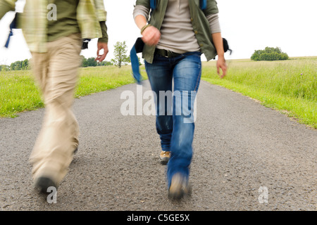 Close-up verschwommenes Portrait Paar Beine Wanderrucksack auf Asphaltstraße Stockfoto