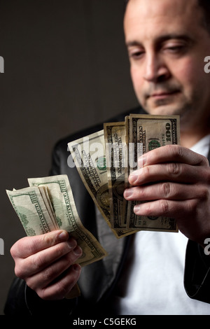 Einem krummen aussehender Mann eine Handvoll von hundert-Dollar-Scheine zu zählen. Geringe Schärfentiefe. Stockfoto