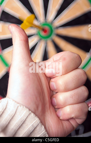 Nahaufnahme eines Dart, der einem Bullen-Auge in der Mitte von der Dartscheibe genagelt hat. Geringe Schärfentiefe. Stockfoto