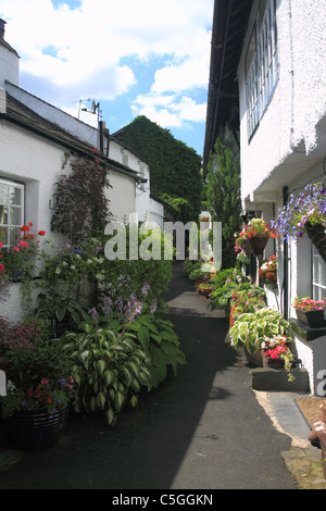 Weiß lackiertes Cottages auf schmalen Dorf Weg mit Displays von Blumen Stockfoto