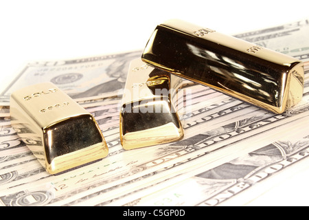 drei große Goldbarren bei vielen Dollarnoten Stockfoto