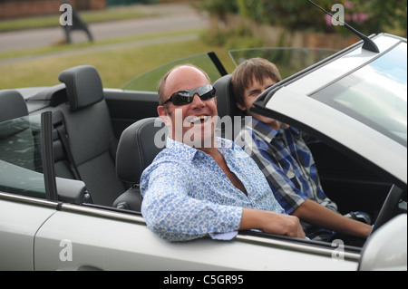 Mann mittleren Alters männlichen Sonnenbrille sitzt in einem oben offenen Wagen Stockfoto