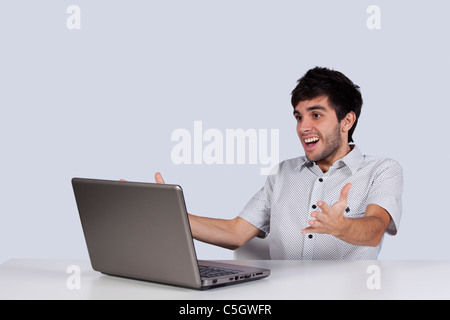 junger Mann überrascht und zufrieden mit etwas, das er auf seinem Laptop sehen Stockfoto