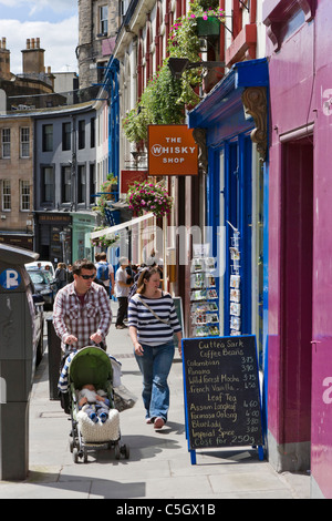 Paar mit jungen baby zu Fuß vorbei an Geschäften auf Grassmarket in Old Town, Edinburgh, Schottland, Großbritannien Stockfoto