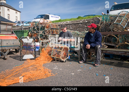 Fischer Netze auf der Hafenpromenade in Eyemouth ausbessern Stockfoto