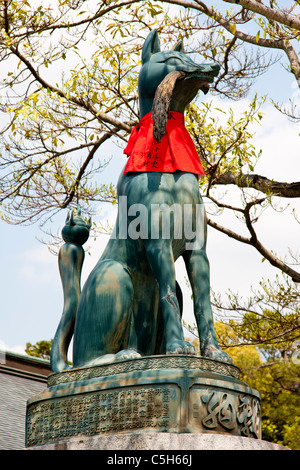 Bronzestatue eines Kitsune, Fuchs, am Inari-Schrein in Fushimi in Kyoto. Er gilt als Hüter, hat einen roten Ruf und eine Garbe Reis im Mund. Stockfoto