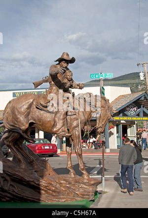 Hier eine kleine Jungs reiten auf einem Pferd in den Armen von einem verwitterten alten Cowboy, Vater oder Großvater vielleicht?, in Jackson Hole, USA. Stockfoto
