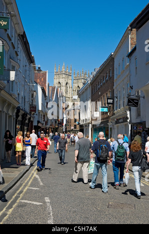 Menschen, die im Sommer das Stadtzentrum mit dem Minster im Hintergrund Von Low Petergate York North Yorkshire England Großbritannien besuchen Stockfoto