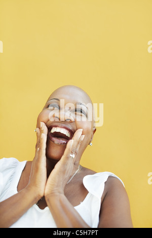 Portrait des afrikanischen 50 Jahre überrascht mit Glatze, lächelnde Frau auf gelbem Hintergrund. Kopf und Schultern, Textfreiraum Stockfoto