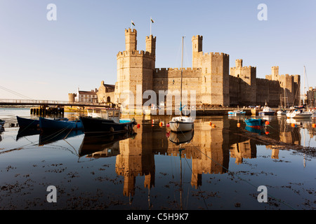 Caernarfon Castle, North Wales, mit festgemachten Booten im Vordergrund Stockfoto