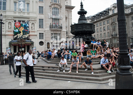 Touristen saßen die Eros-Statue am Piccadilly Circus in London mit dem Kriterium Theater zeigt die 39 Stufen Stockfoto