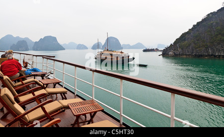 Junk-e-traditionelles Boot Passagiere in Ha Long Bucht, Vietnam, gesehen vom Deck des Kreuzfahrtschiffes Emeraude. Stockfoto