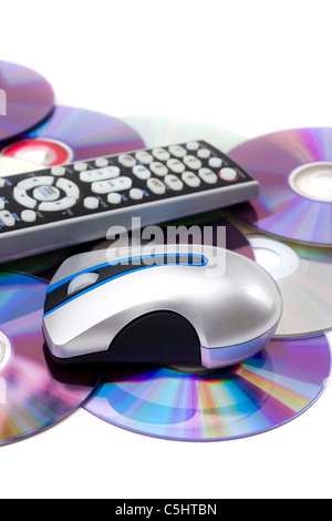 TV-Fernbedienung und Computer-Maus auf einem Haufen verstreuten DVDs über weißen isoliert. Stockfoto