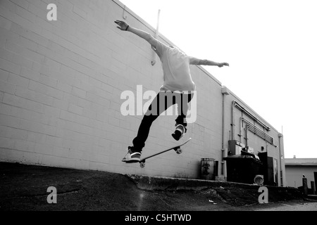 Ein Junge Skateboarder einen Stunt in einem städtischen Gebiet zu tun. Stockfoto