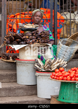 Afrikanische Anbieter ruht auf Marktstand verkaufen geräucherten Fisch und frischen Tomaten, Kaneshie Markt, Accra, Ghana Stockfoto