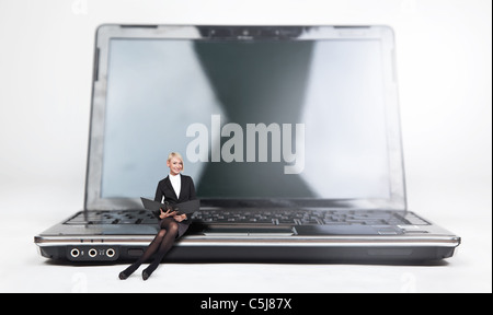 Junge Geschäftsfrau sitzen auf einem Laptop, isoliert auf weiss Stockfoto
