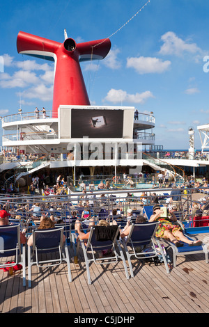 Kreuzfahrt-Passagiere beobachten große Fernseher mit Flachbildschirm draußen auf dem Deck des Kreuzfahrtschiffes Carnival Triumph im Golf von Mexiko Stockfoto