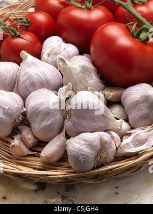 Knoblauch und rote, reife Tomaten in einem Weidenkorb Stockfoto