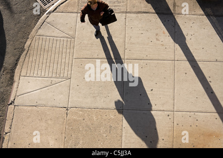 Eine Frau in New York City wirft einen langen Schatten am späten Nachmittag. Stockfoto