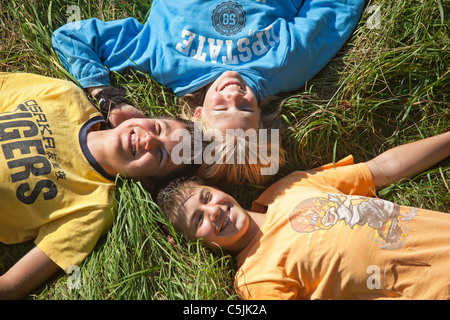 drei Jugendliche, die nebeneinander auf einer Wiese liegend Stockfoto