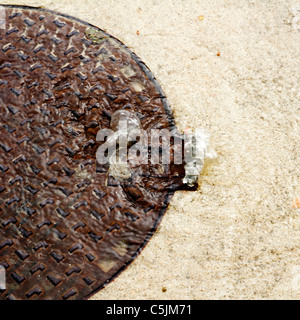 Schacht über fließende Wasser an einem regnerischen Tag mit Kanalisation problem Stockfoto