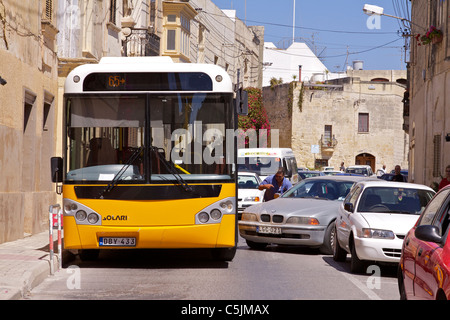 Eine gelbe, die maltesischen Bus versucht, eine kaputte Auto in einer engen Straße in Mosta quetschen Stockfoto