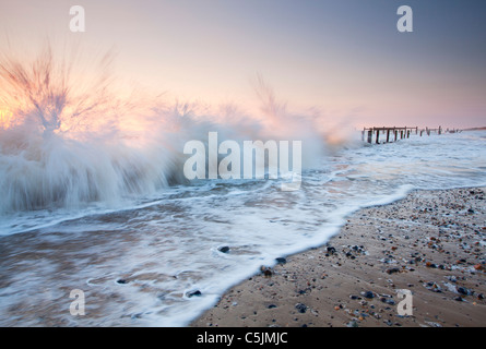 Kräftige Wellen Absturz gegen die verlassenen aus Holz und Metall Meer Abwehrkräfte auf Happisburgh Strand an der Küste von Norfolk Stockfoto