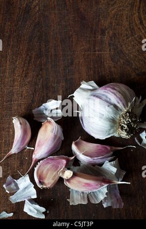 Eine Glühbirne lila Streifen Knoblauch, die Hälfte davon getrennt in einzelne Zehen auf ein Schneidebrett. Stockfoto