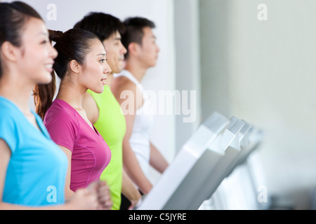 Vier Menschen laufen auf Laufbändern Stockfoto