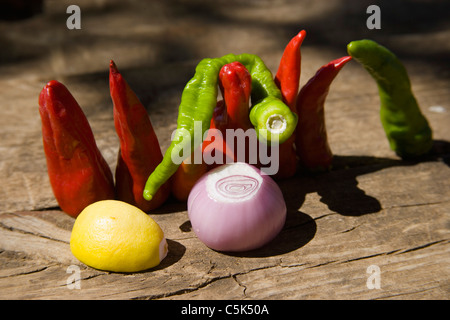 Rote Pfefferkörner, grüne Pfefferkörner, 1 Zwiebel und ein Viertel einer Zitrone auf Holztisch Stockfoto